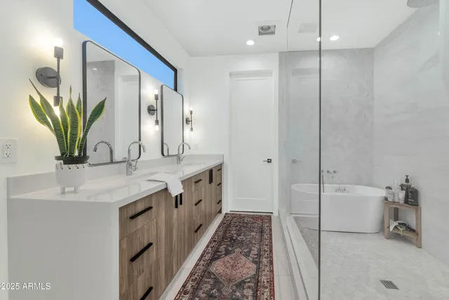 a bathroom with a double vanity sink a large mirror and a bathtub