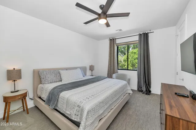 a bedroom with a bed a window and a chandelier