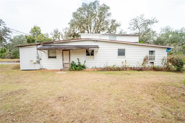an aerial view of a house with large trees and sitting area