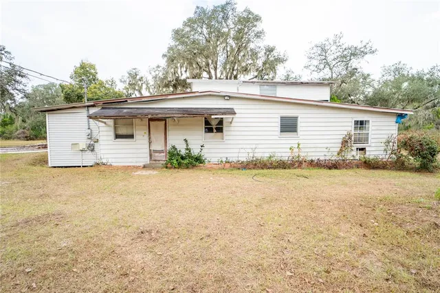 an aerial view of a house with large trees and sitting area