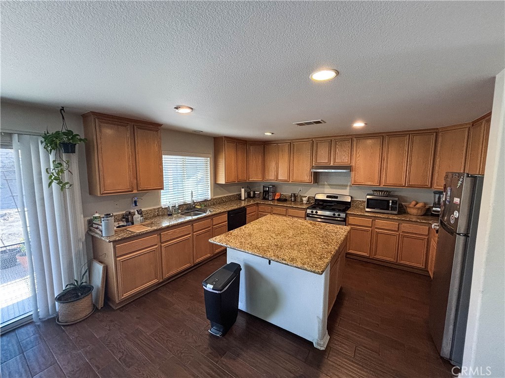 29120 Turtle Rock Court Menifee, CA 92587 - Photo 8 of 40 a kitchen with stainless steel appliances granite countertop a stove a sink dishwasher a refrigerator and a oven with wooden floor