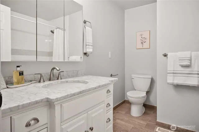 a bathroom with a granite countertop toilet sink and mirror