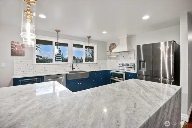 a large kitchen with stainless steel appliances a large counter top a stove a refrigerator and a sink