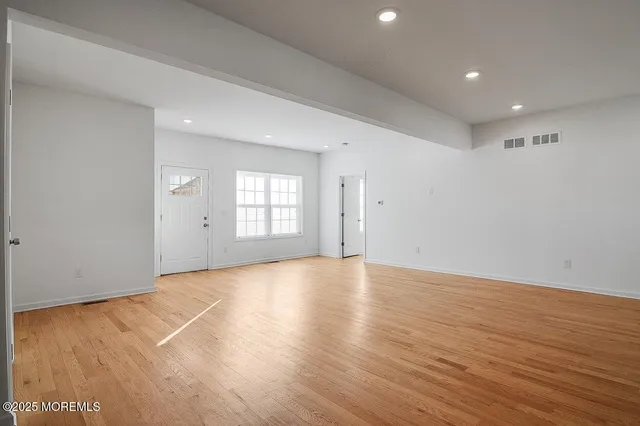 a view of an empty room with wooden floor and window