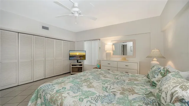 a bedroom with a bed and a flat tv screen on dresser