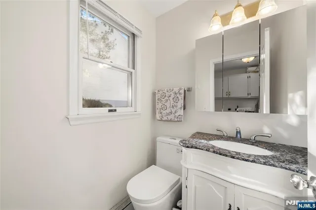a bathroom with a granite countertop toilet sink and mirror