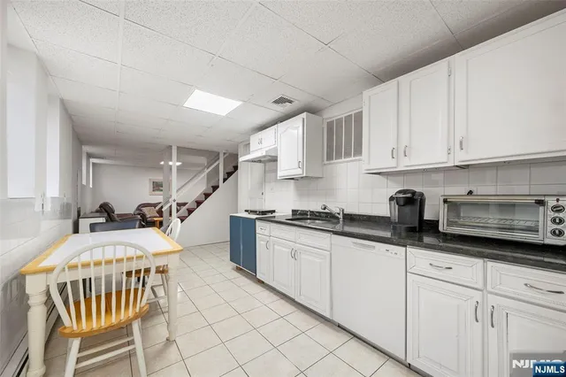 a kitchen with stainless steel appliances granite countertop a stove a sink dishwasher and white cabinets with wooden floor