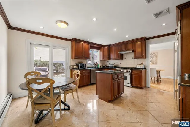 a kitchen with stainless steel appliances granite countertop a stove top oven a sink a dining table and chairs with wooden floor