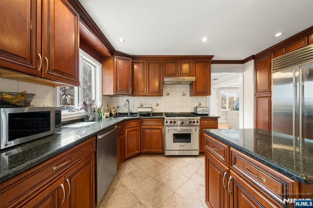 a kitchen with stainless steel appliances granite countertop a stove a sink and a refrigerator