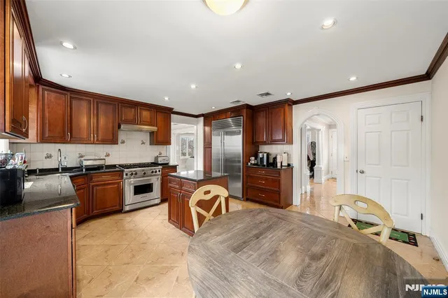 a kitchen with granite countertop a refrigerator stove top oven and sink