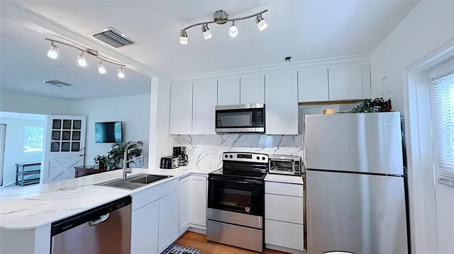 a kitchen with stainless steel appliances a refrigerator sink and microwave