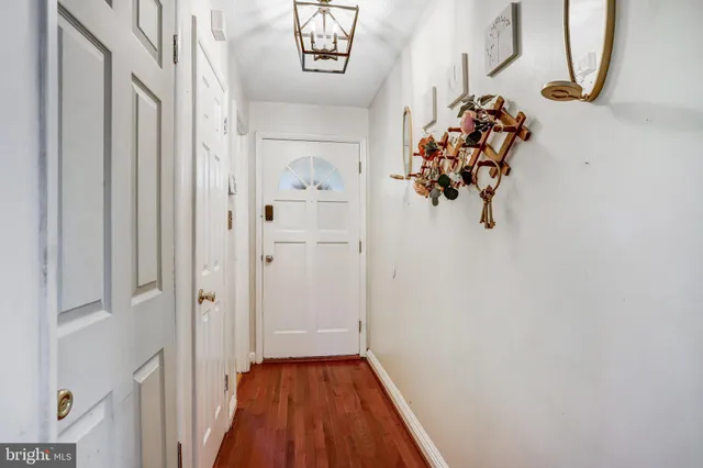 a view of a hallway with wooden floor and a chandelier
