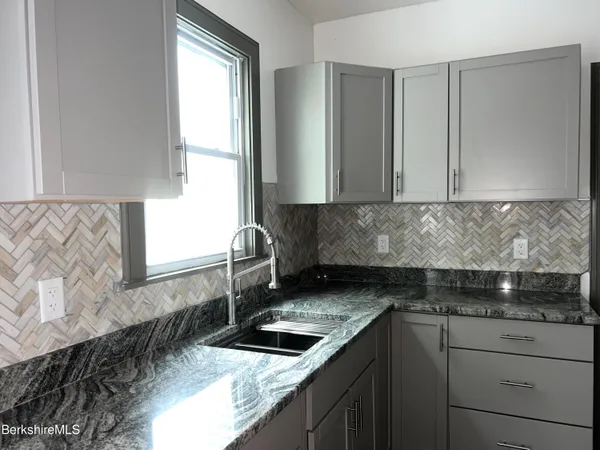a kitchen with granite countertop a sink and a stove