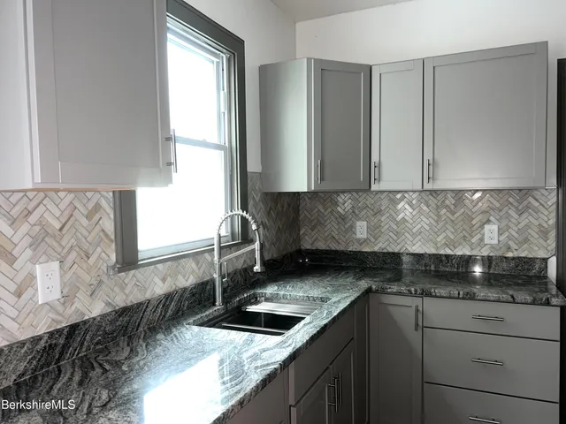 a kitchen with granite countertop a sink and a stove