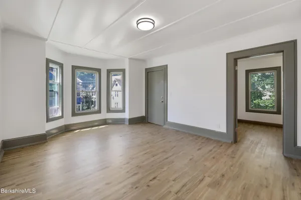 an empty room with wooden floor and window