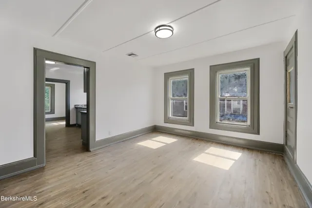 an empty room with wooden floor and windows