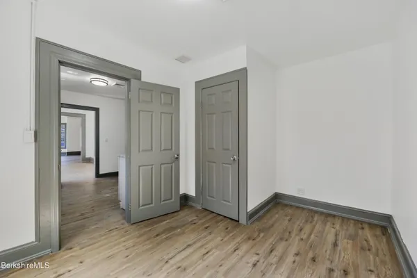 a view of a kitchen with an empty room and wooden floor