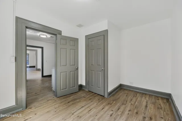 a view of a kitchen with an empty room and wooden floor