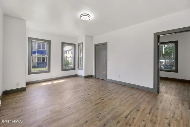 an empty room with wooden floor and windows