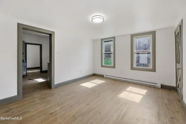 a view of an empty room with window and wooden floor