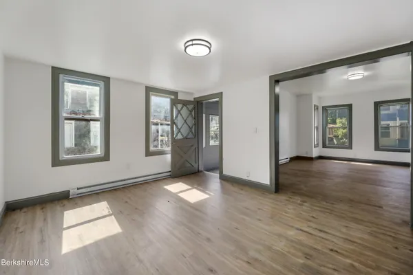 an empty room with wooden floor and windows
