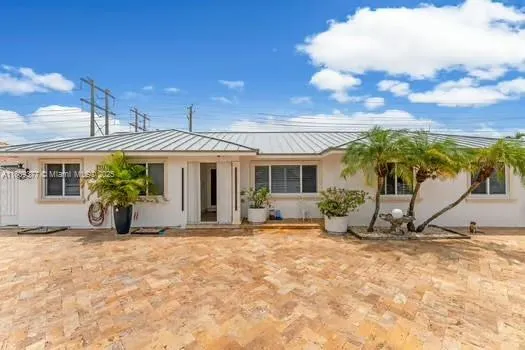 a view of a house with potted plants and a large tree