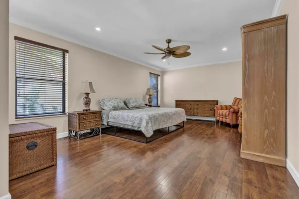 a bedroom with a bed a dresser and wooden floor