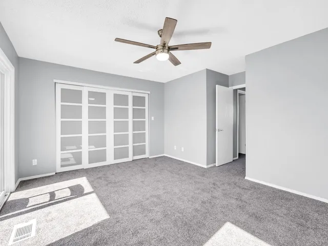 an empty room with windows and ceiling fan