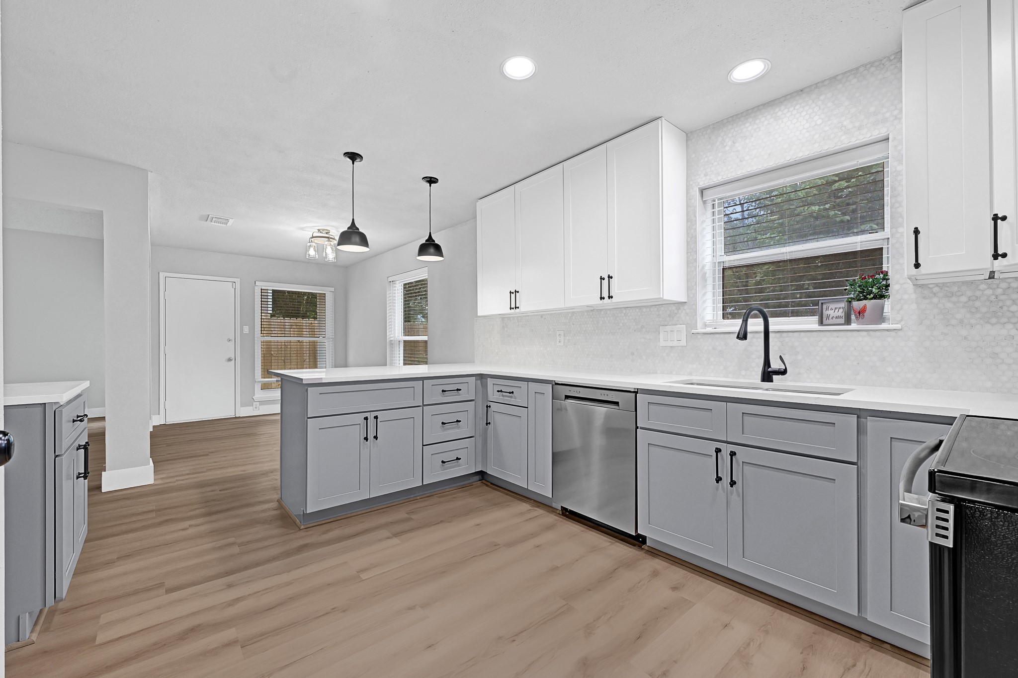 a large kitchen with stainless steel appliances granite countertop a sink dishwasher a stove and white cabinets with wooden floor