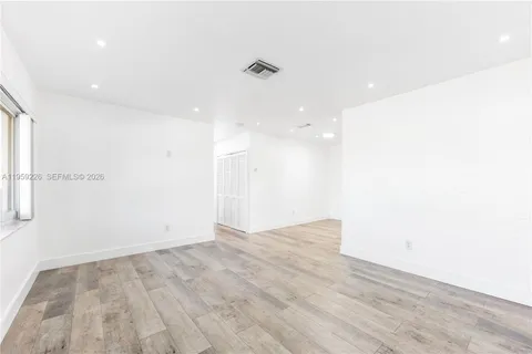 a view of empty room with wooden floor and windows