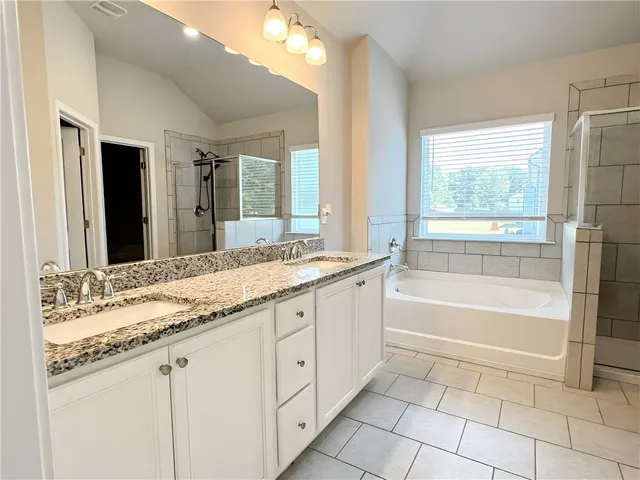 a bathroom with a granite countertop sink a mirror and a bathtub