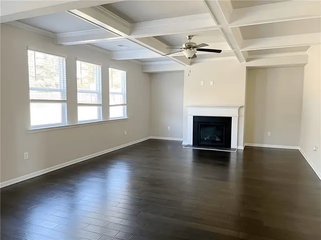 an empty room with wooden floor fireplace and windows