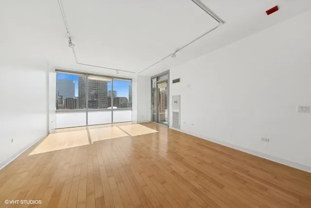 a view of an empty room with wooden floor and fence