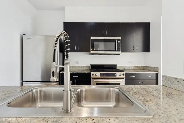 a kitchen with stainless steel appliances kitchen island granite countertop a sink and a microwave