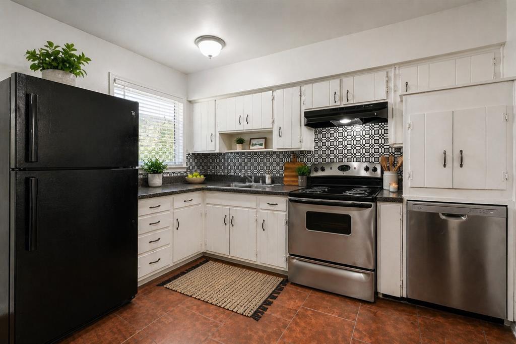 1905 South Cooper Street Arlington, TX 76010 - Photo 8 of 15 Kitchen featuring white cabinetry, dark countertops, a patterned tile backsplash, stainless steel appliances, and terra cotta-style flooring