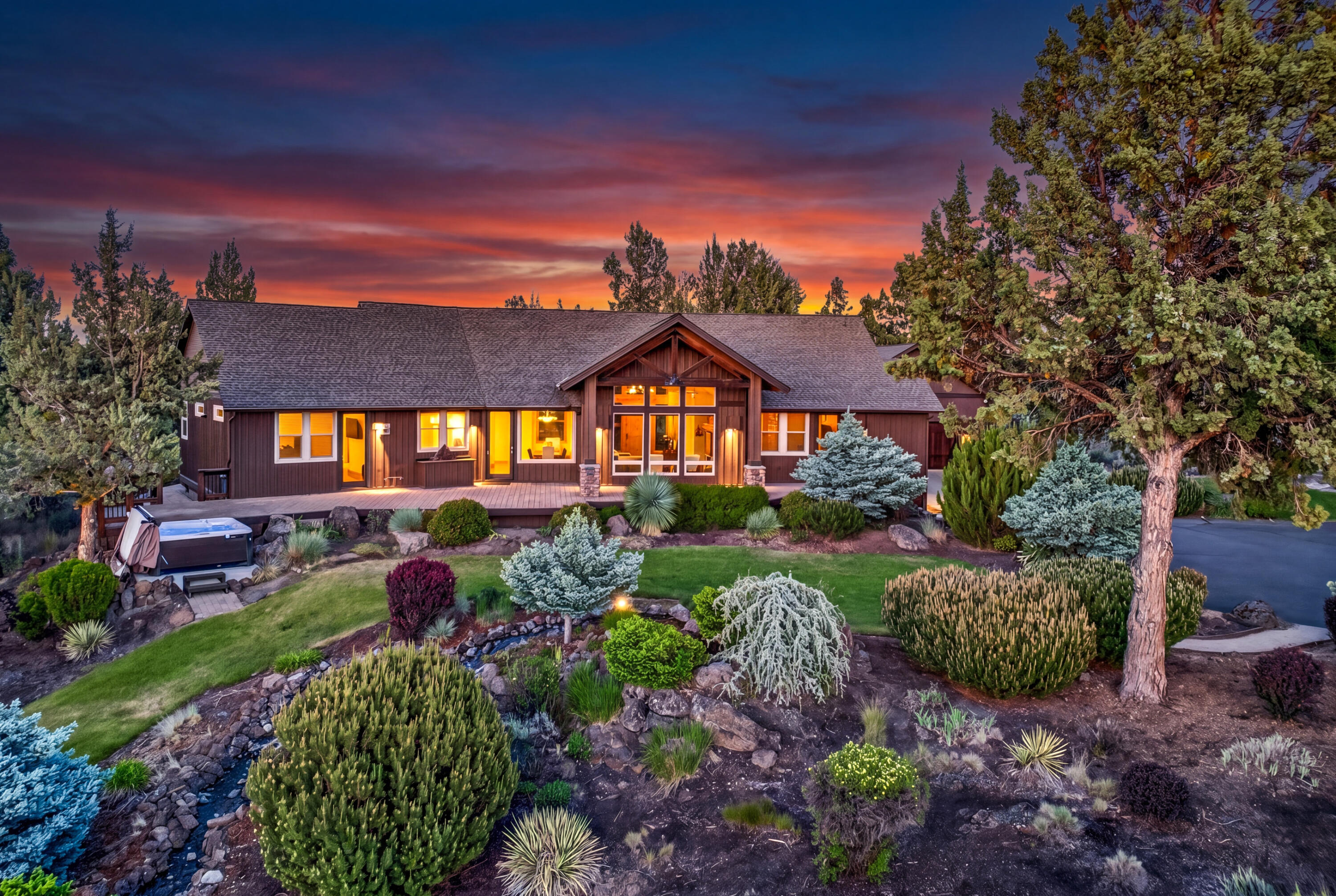 64145 Hunnell Road Bend, OR 97703 - Photo 2 of 65 The custom PacWest-built single-level residence glows at sunset, surrounded by mature landscaping, outdoor living areas and a sweeping Cascade Mountain-view setting.