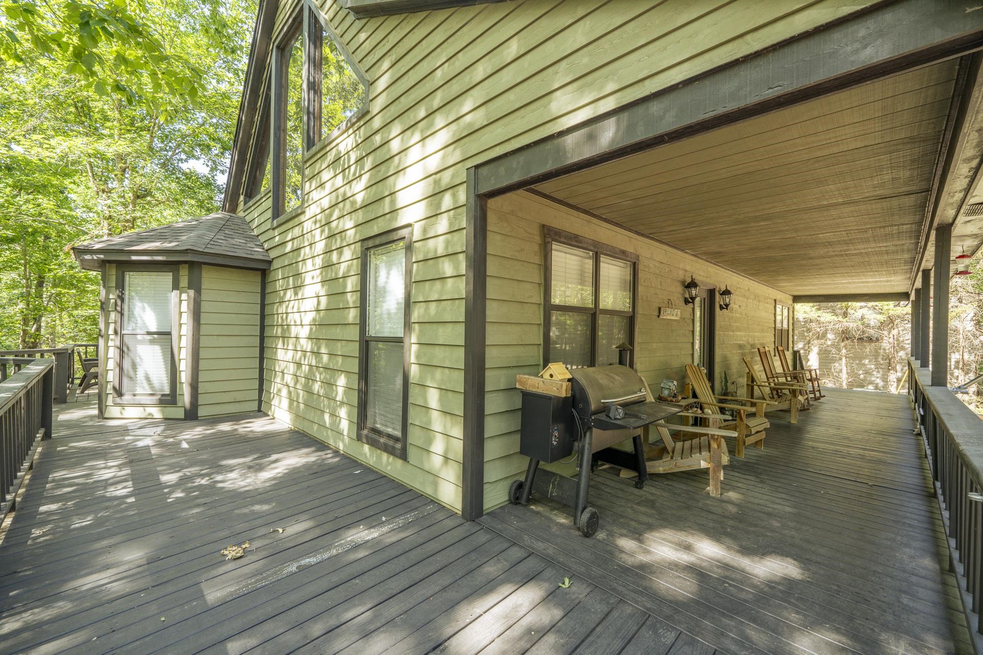 435 Murray Lane Counce, TN 38326 - Photo 6 of 34 Expansive outdoor deck featuring a covered porch with a wood-finish ceiling, green horizontal siding, multiple windows, and a surrounding wooded environment