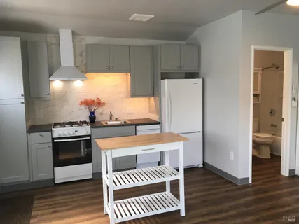 a kitchen with stainless steel appliances a refrigerator a sink and white cabinets
