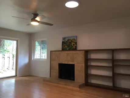 a view of an empty room with a window and fireplace