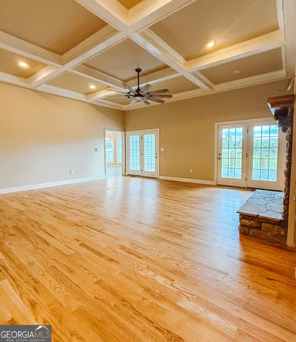 a view of an empty room with wooden floor and a fan