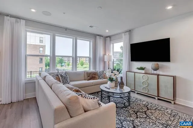 a living room with furniture a flat screen tv and a large window