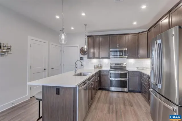 a kitchen with kitchen island stainless steel appliances a sink stove and refrigerator