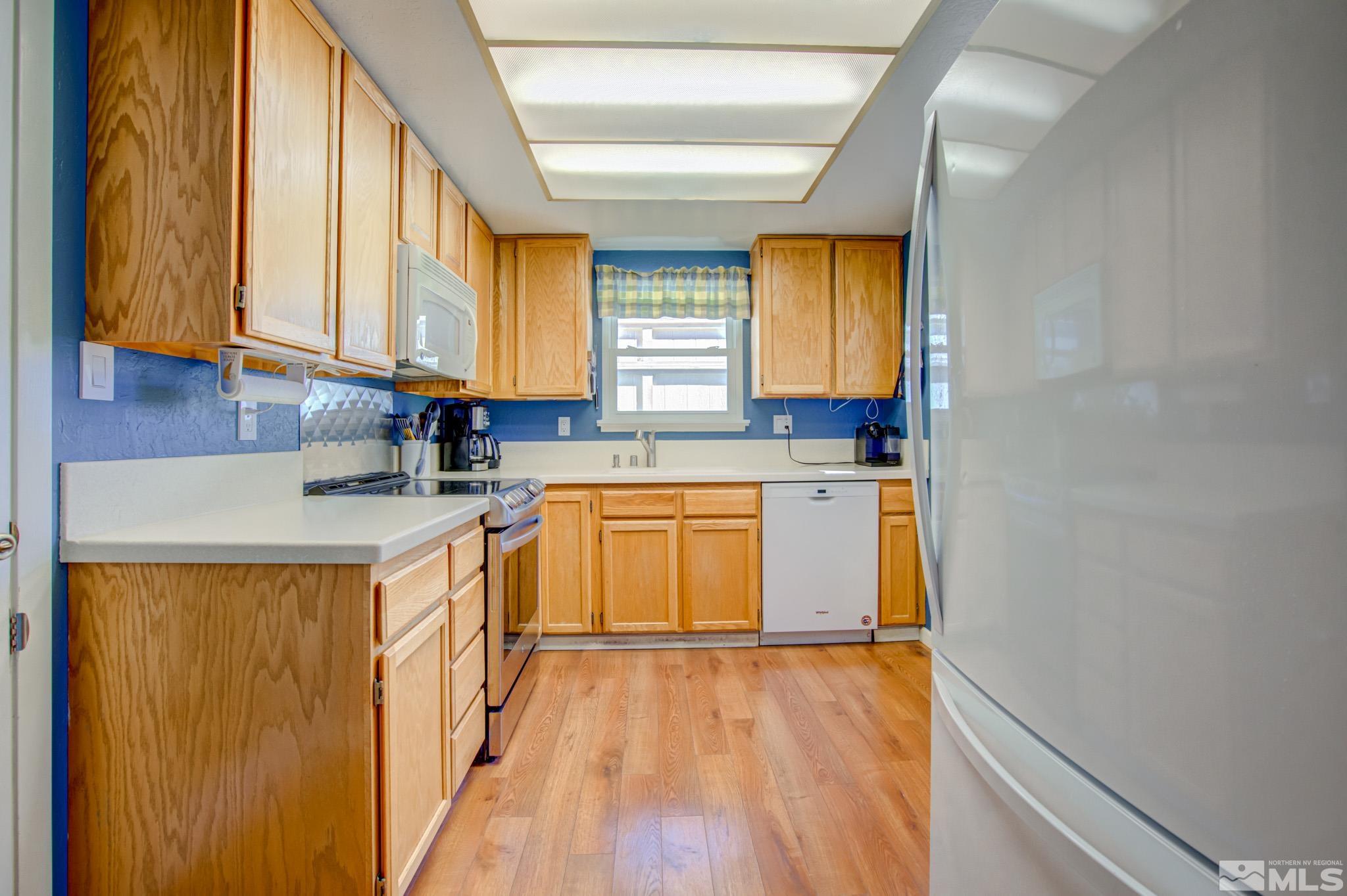 1208 Laredo Court Reno, NV 89503 - Photo 11 of 30 a kitchen with granite countertop wooden floors and white stainless steel appliances
