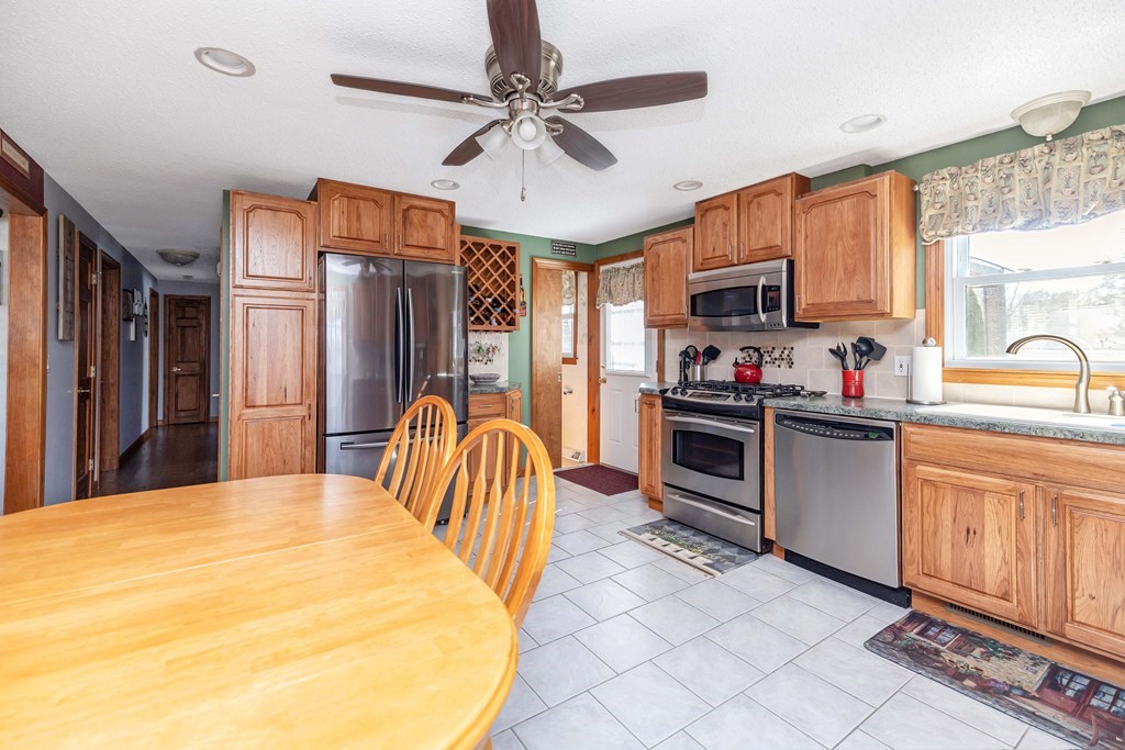 20 Murphy Lane Chicopee, MA 01020 - Photo 3 of 22 a kitchen with stainless steel appliances granite countertop a stove top oven a sink dishwasher a dining table and chairs with wooden floor