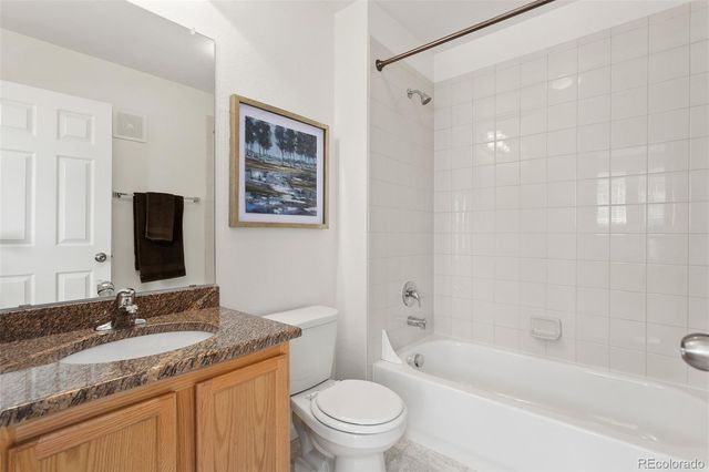 a bathroom with a granite countertop toilet a sink and a bathtub