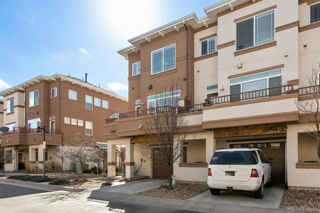 a front view of a building with lot of cars and trees