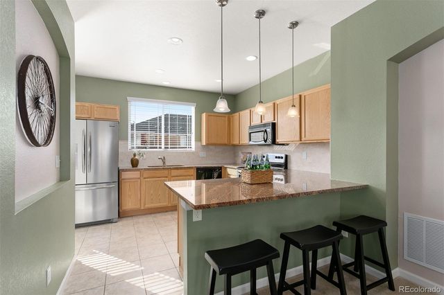 a kitchen with stainless steel appliances granite countertop a kitchen island a stove a table and chairs