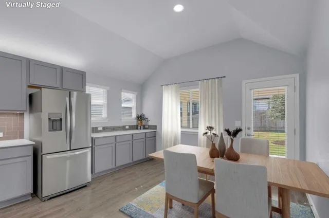a kitchen with refrigerator a stove dining table and chairs