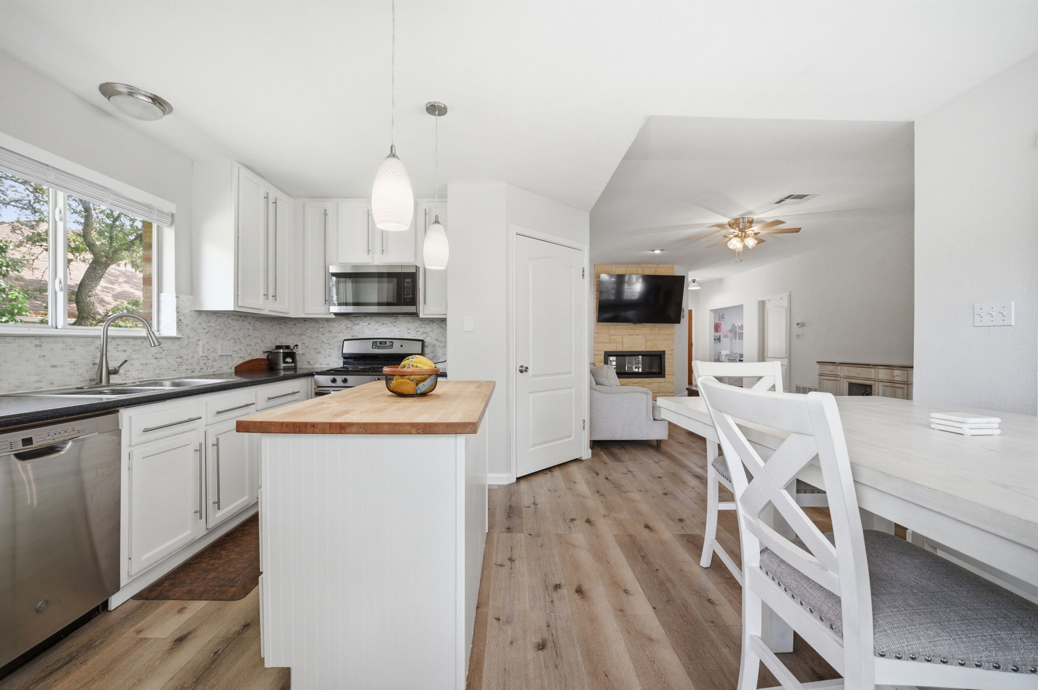 9024 Heiden Lane Austin, TX 78749 - Photo 10 of 28 Kitchen featuring white cabinetry, a stainless steel dishwasher, an undermount sink, a wood-finish island countertop, and wood-finish flooring