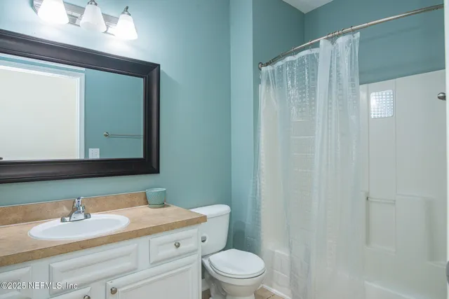 a bathroom with a granite countertop sink toilet a mirror and shower